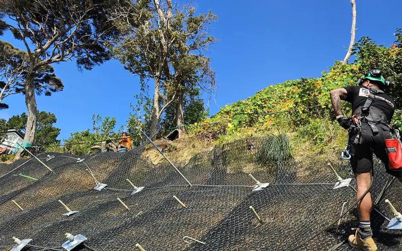 Erosion control matting anchored across a bare slope