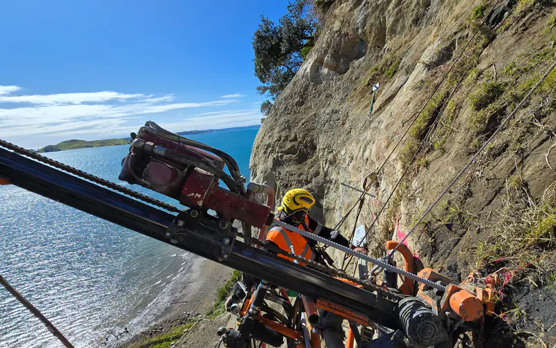 Drilling rig installing soil nails into a cut slope face