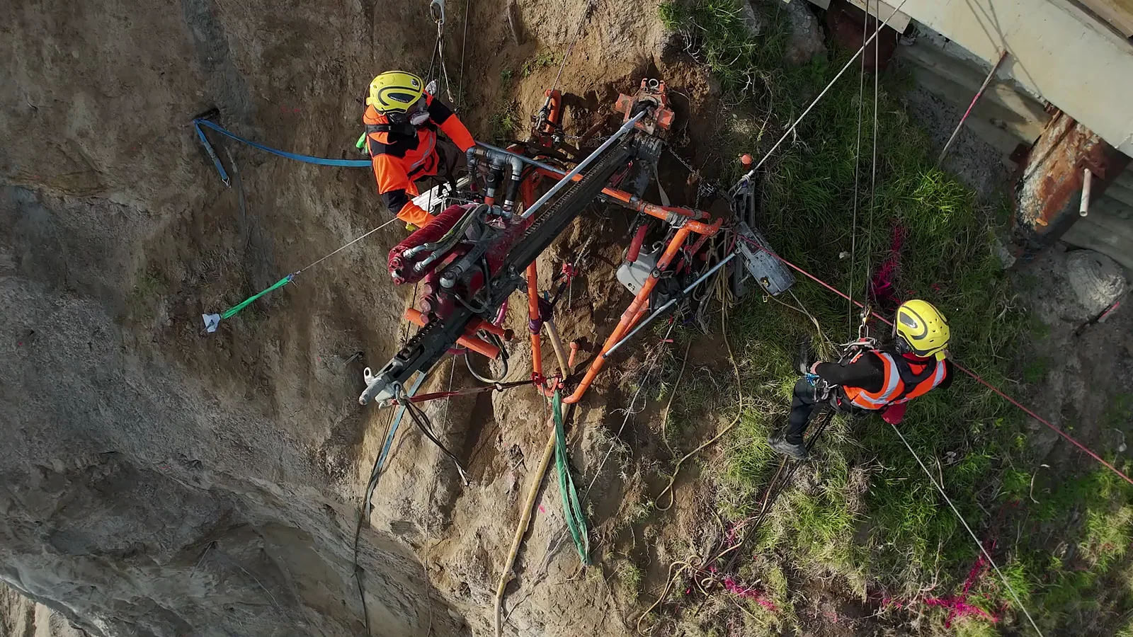 Geo Mana rope-access crew drilling a steep residential cliff face